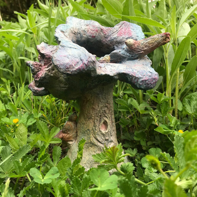 sculpture d'un arbre avec un nid d'oiseau au milieu d'un jardin
